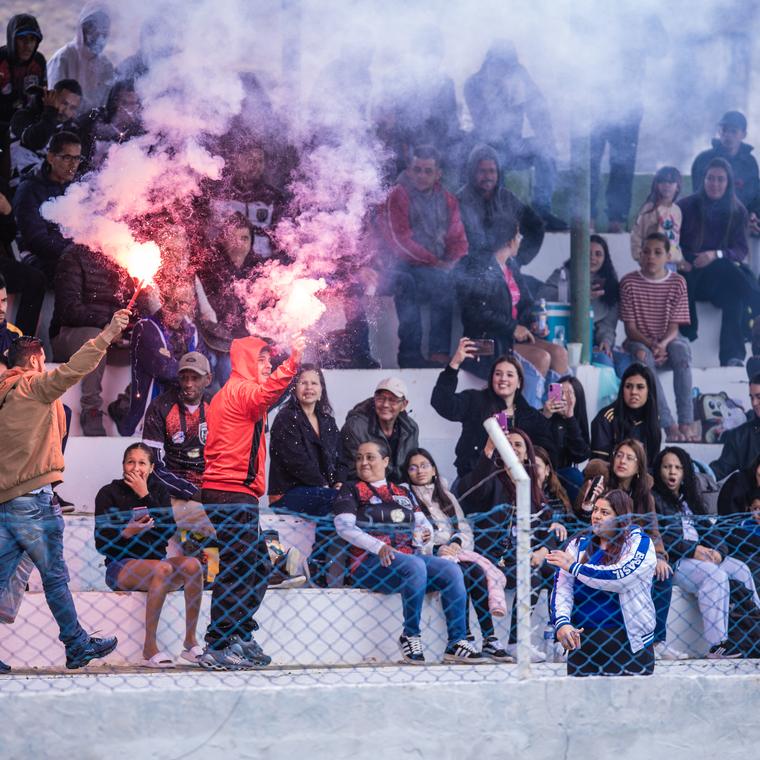 Sinalizador aceso na torcida, atrás do alambrado