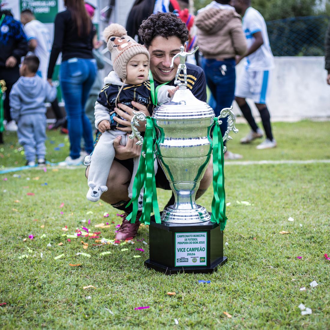 Criança no colo ao lado da taça, depois da final